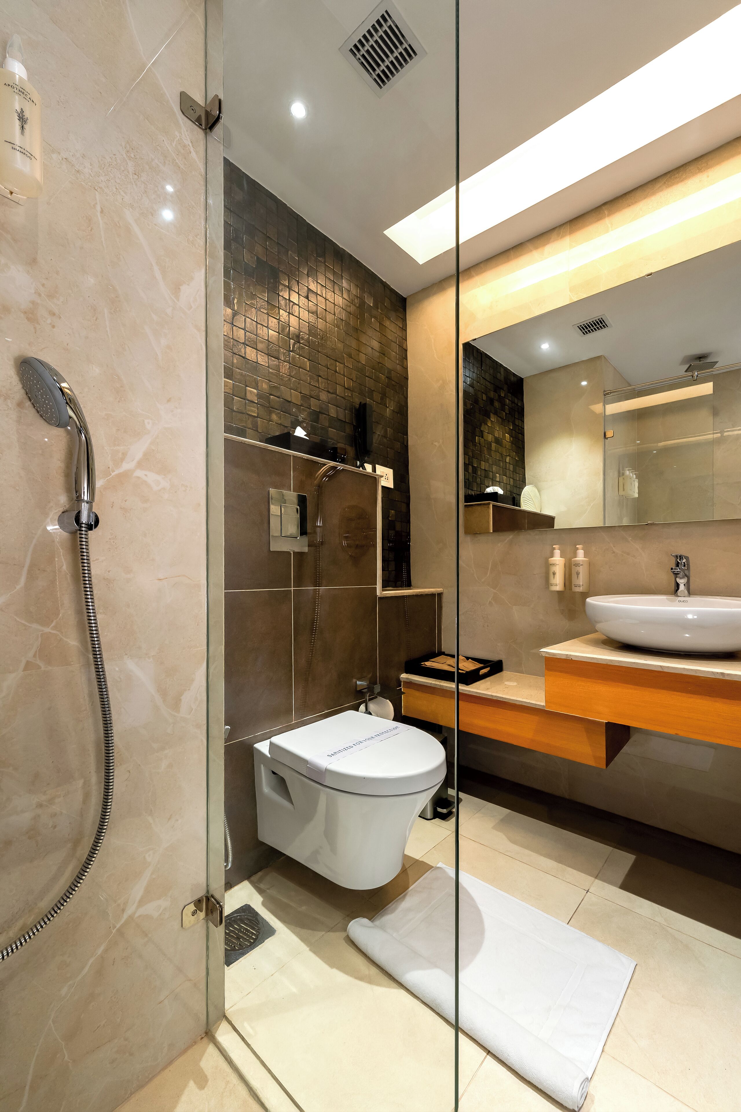 Une salle de bain moderne avec une douche à parois de verre, des toilettes blanches et un meuble-lavabo.