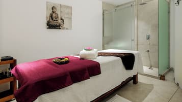 A modern bedroom with a bed, a glass shower enclosure, and a Buddha statue on the wall.
