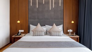 A modern hotel room with a large bed, wooden headboard, two bedside tables with lamps, and a telephone. - TIARA BY MPS (Kozhikode)