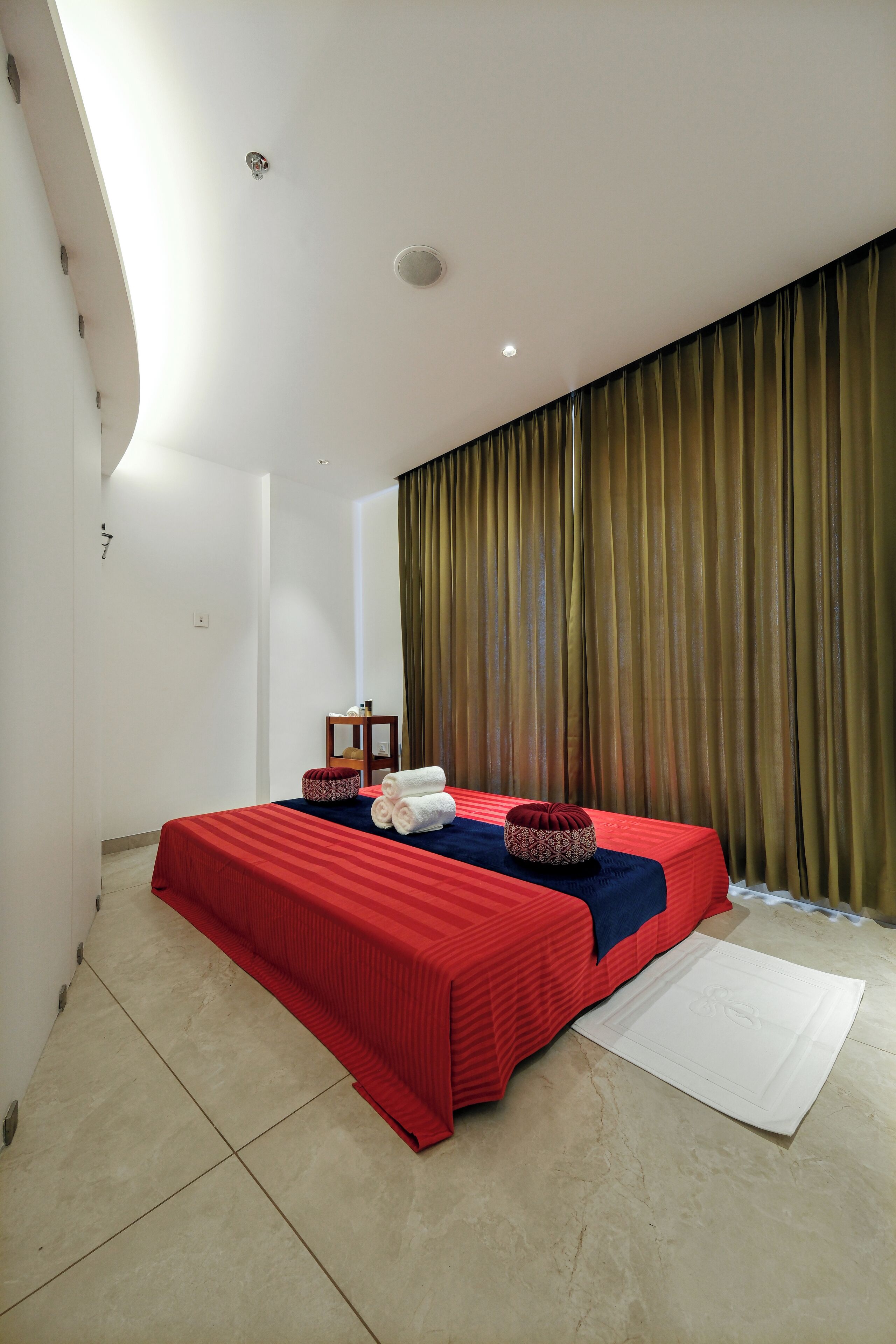 Een hotelkamer met een bed, een klein tafeltje en een gordijn.