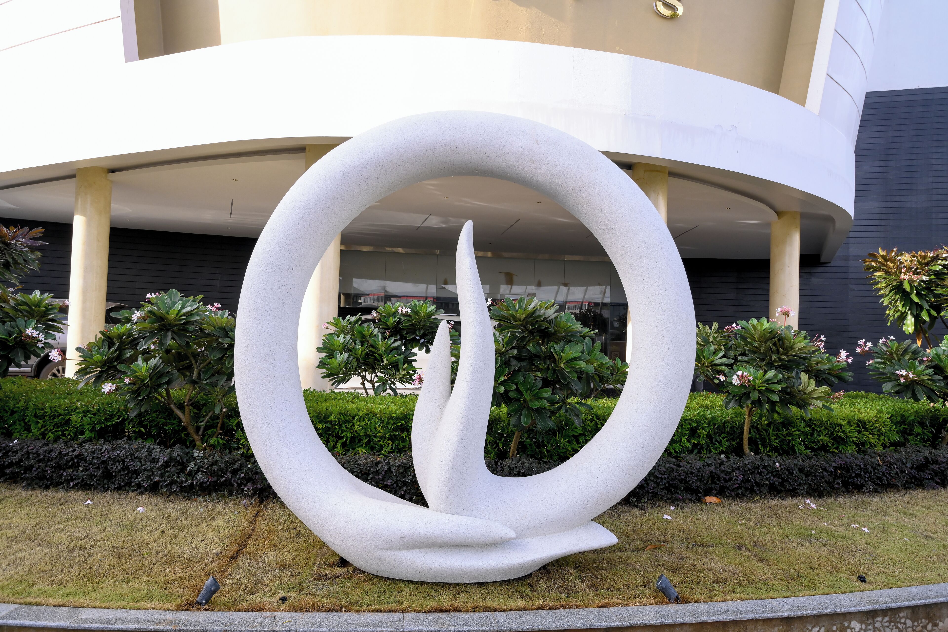 Un edificio moderno con una escultura circular en primer plano.