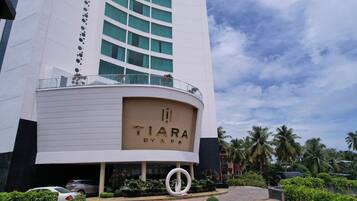 A modern hotel with a curved facade, a prominent entrance with a circular design element, and a view of palm trees in the background.