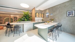 A modern kitchen with a central island, bar stools, and a large potted plant. - Weave Studios - Kowloon West (Kowloon)