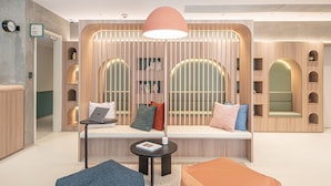 A modern workspace with a curved bench, a laptop, and a small table with a book. - Weave Studios - Kowloon West (Kowloon)