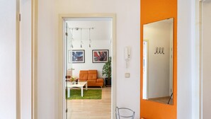 A hallway leading to a living area with a sofa, coffee table, and artwork on the wall.