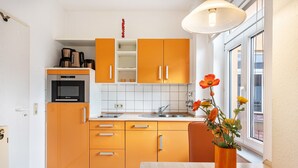 A kitchen with orange cabinets, a microwave, and a sink.