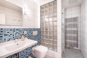 A bathroom with a white sink, a toilet, and a glass shower enclosure.