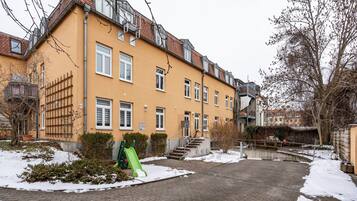 Ein mehrstöckiges Wohngebäude mit Ziegelverkleidung, einer grünen Rutsche und verschneitem Gelände.