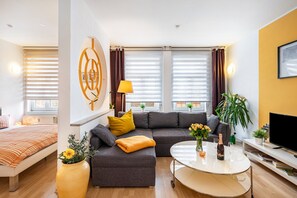A modern living room with a sofa, a coffee table, a TV, and a bed.