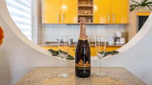 Una botella de vino sobre una mesa con dos copas, en una cocina con armarios amarillos.