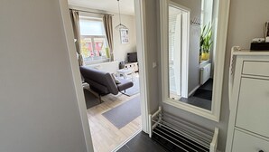 Ein Flur, der in ein Wohnzimmer mit einer Couch, einem Fernseher und einer Heizung führt.