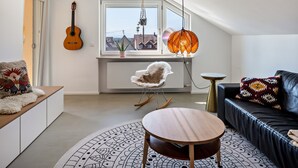 A modern living room with a guitar, a rocking chair, a round table, and a sofa.