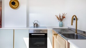 A modern kitchen with a Bosch oven, a stainless steel sink, and a vase with dried flowers.