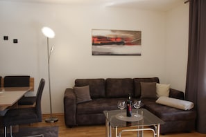 Un salon moderne avec un canapé marron, une table basse en verre, un lampadaire et un tableau accroché au mur.