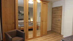 Una habitación con un armario de madera, una cama, una silla y una puerta.