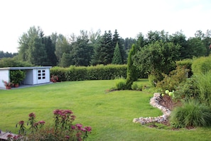 Un jardin bien entretenu, agrémenté d’un petit abri de jardin, de haies soigneusement taillées et d’une variété de plantes.