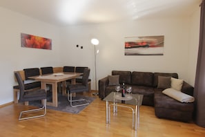 Un salon moderne avec une table à manger, un canapé et deux tableaux accrochés aux murs.