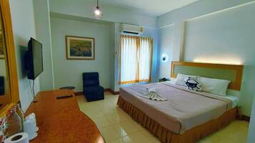 Une chambre d’hôtel équipée d’un lit, d’un bureau, d’une chaise, d’une télévision et d’un appareil de climatisation.