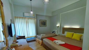 A hotel room with two beds, a desk with a mirror, a television, and an air conditioning unit. - Polkadot Cafe&Hotel (Phitsanulok)