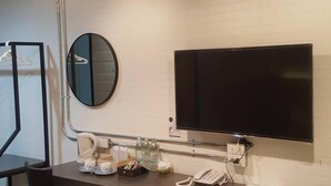 A modern room with a desk, chair, and a flat-screen TV mounted on the wall. - Polkadot Cafe&Hotel (Phitsanulok)