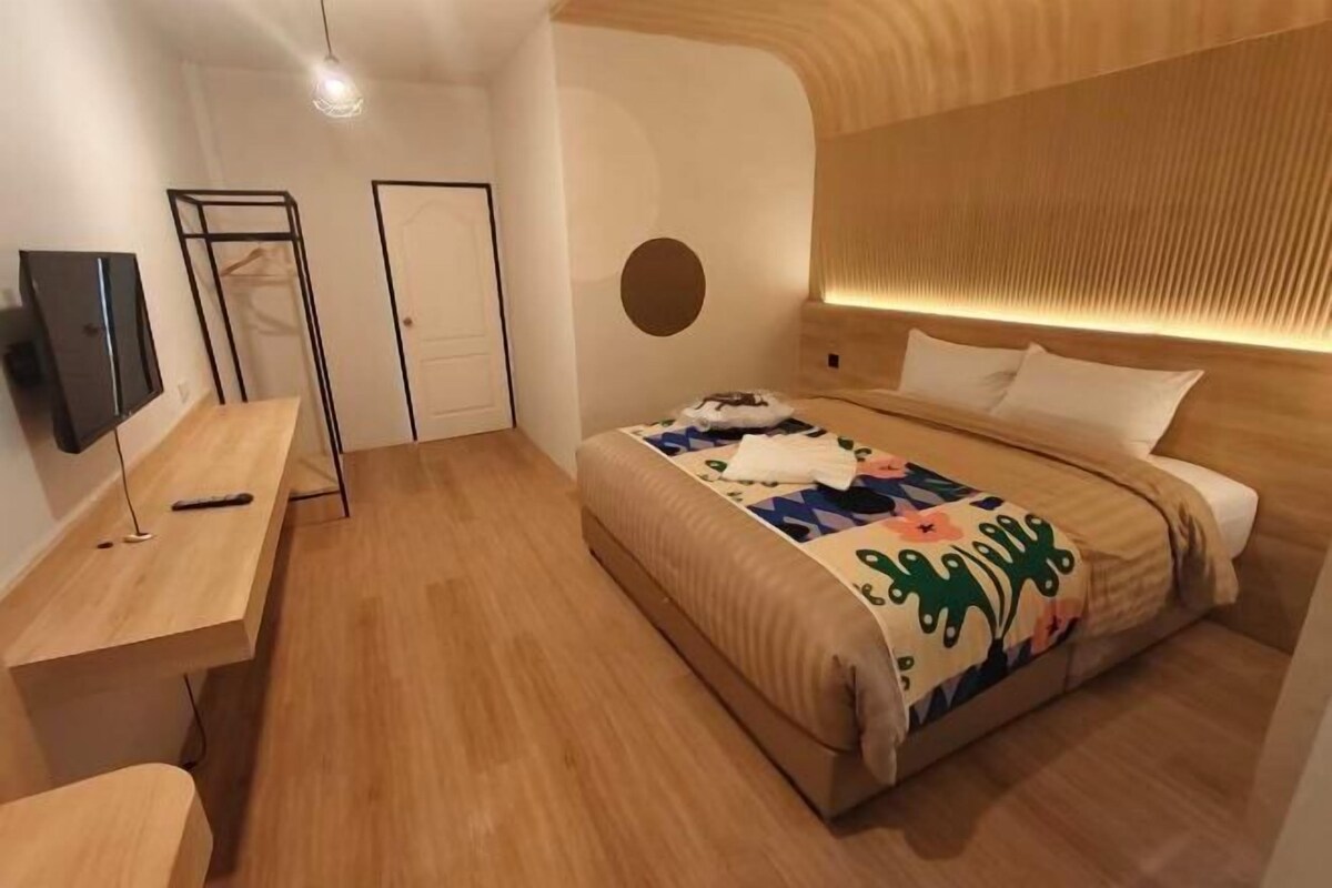 Ein modernes Schlafzimmer mit einem Holzbett, einem Schreibtisch und einem Fernseher.