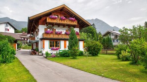 Un chalet traditionnel doté d’un balcon en bois, d’une entrée bien visible et d’un chemin menant au bâtiment.