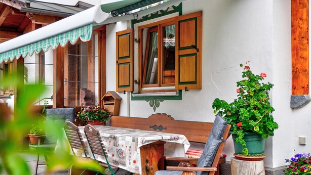 Un banc en bois avec une table, un tabouret en bois et une plante en pot.