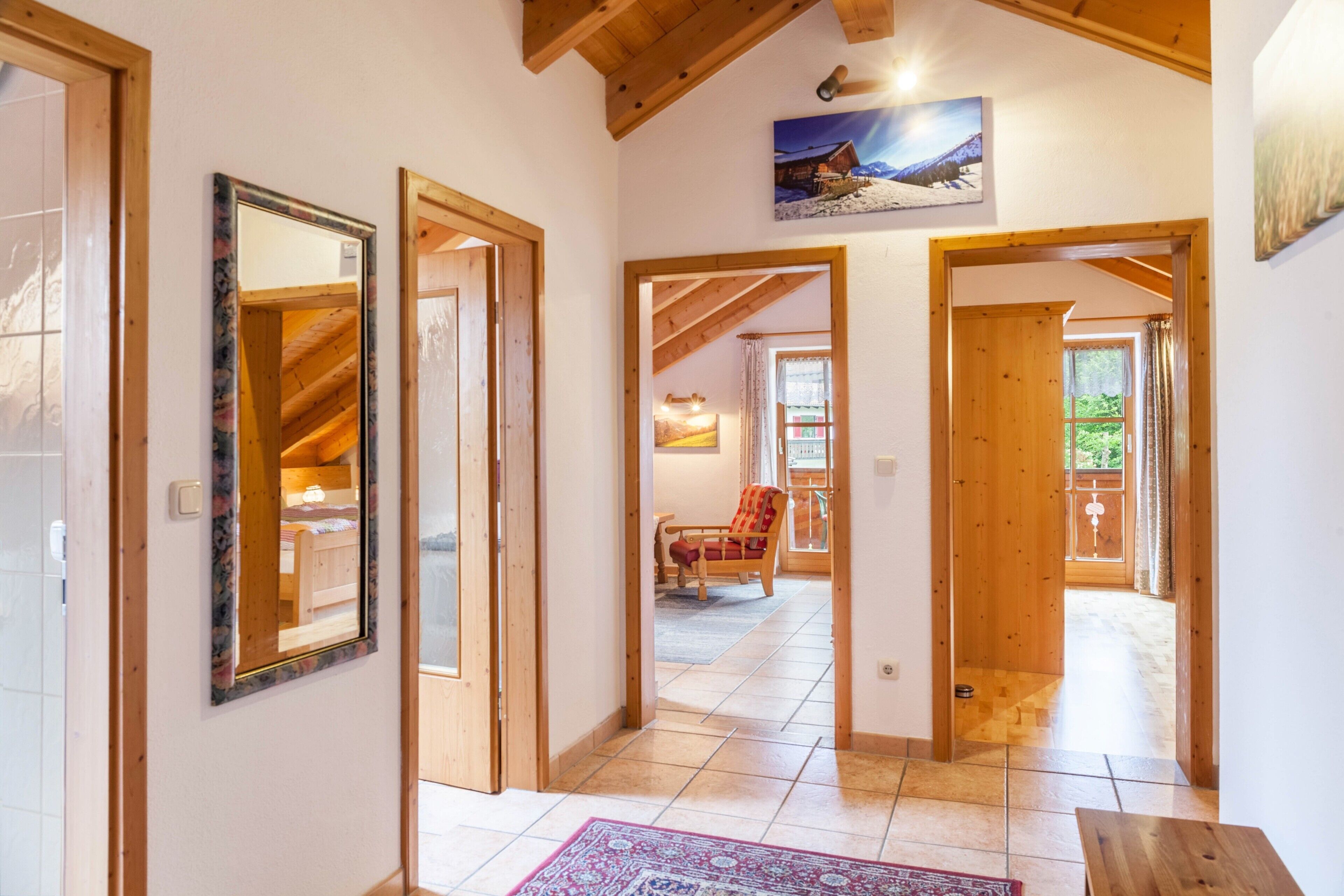 Un couloir avec des portes en bois, un tapis et un tableau accroché au mur.
