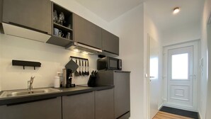 Eine moderne Küche mit integriertem Mikrowellenherd, einer Kaffeemaschine und einem Spülbecken.