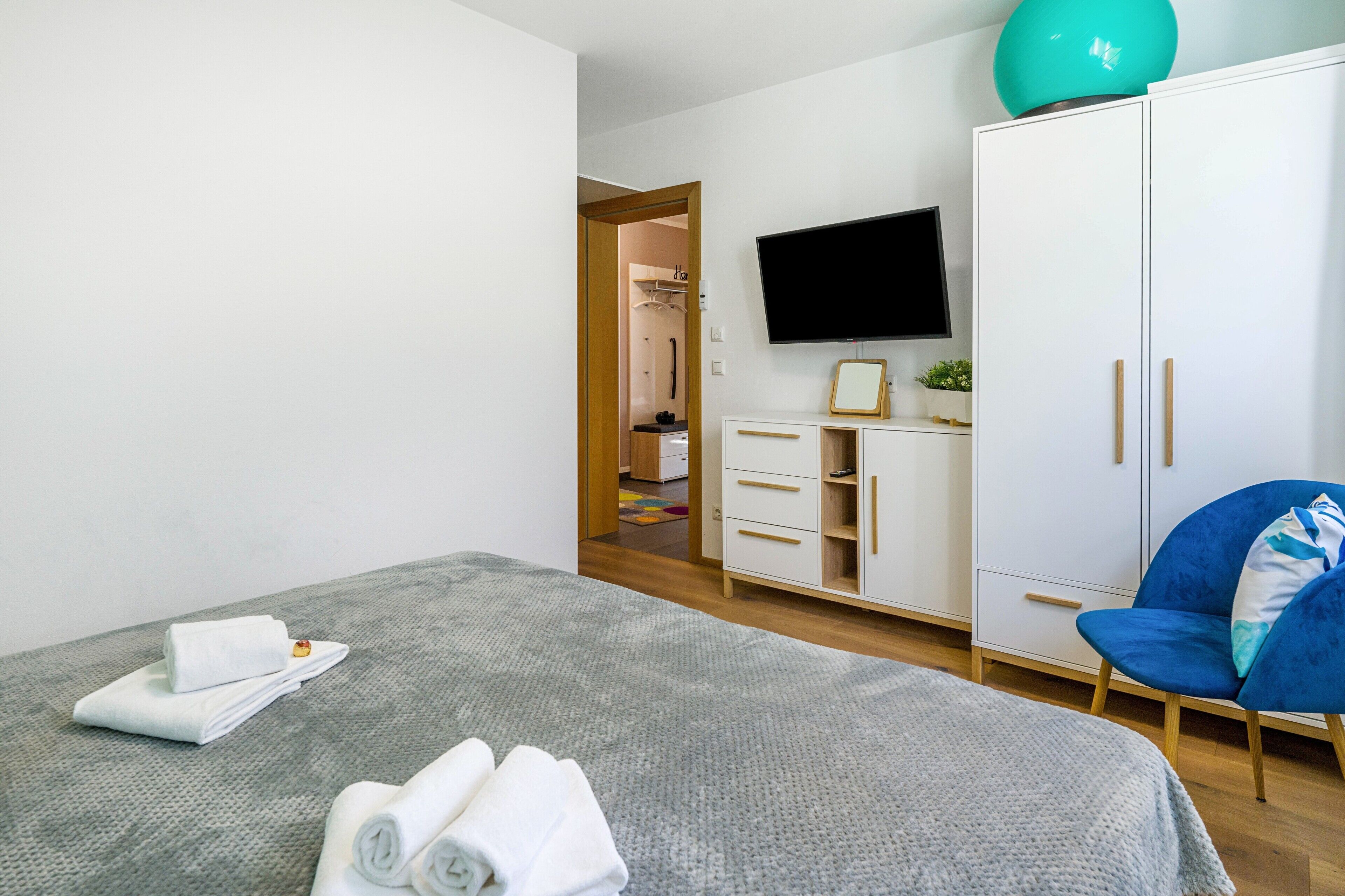 Une chambre à coucher avec un lit, une armoire, une télévision et une chaise.