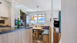 Une cuisine moderne dotée d’un îlot central en bois, d’appareils électroménagers intégrés et d’un coin repas avec un banc.