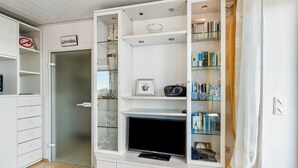 Una habitación con mueble empotrado para entretenimiento, puerta de cristal y estantería.
