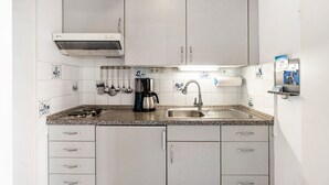 Una cocina con estufa a gas, pileta y alacenas.