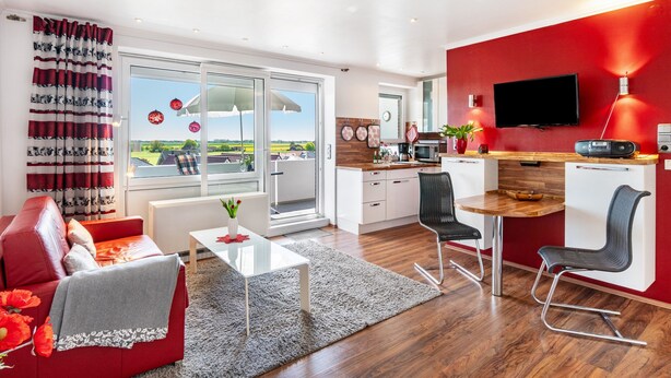 Una sala de estar moderna con un sofá rojo, una mesita de centro y vistas al exterior.