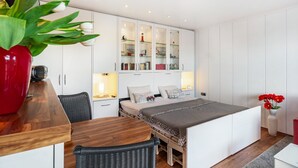 Un dormitorio moderno con cama, mesitas de noche, armario y una zona de comedor con mesa y sillas.
