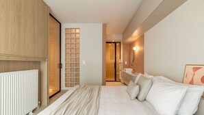 A modern hotel room with a large bed, a wooden wardrobe, a bathroom with a mirror, and a view into the hallway. - Culture Retreat 1 near Archaeological Museum (Athina)