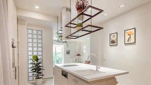 A modern kitchen with a central island, pendant lighting, and a view of the adjacent living area. - Culture Retreat 1 near Archaeological Museum (Athina)