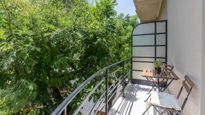 Ein Balkon mit Tisch und Stühlen, umgeben von üppigem Grün.