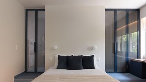 Ein modernes Schlafzimmer mit einem großen Bett, einer Schiebetür und Blick auf Grün.