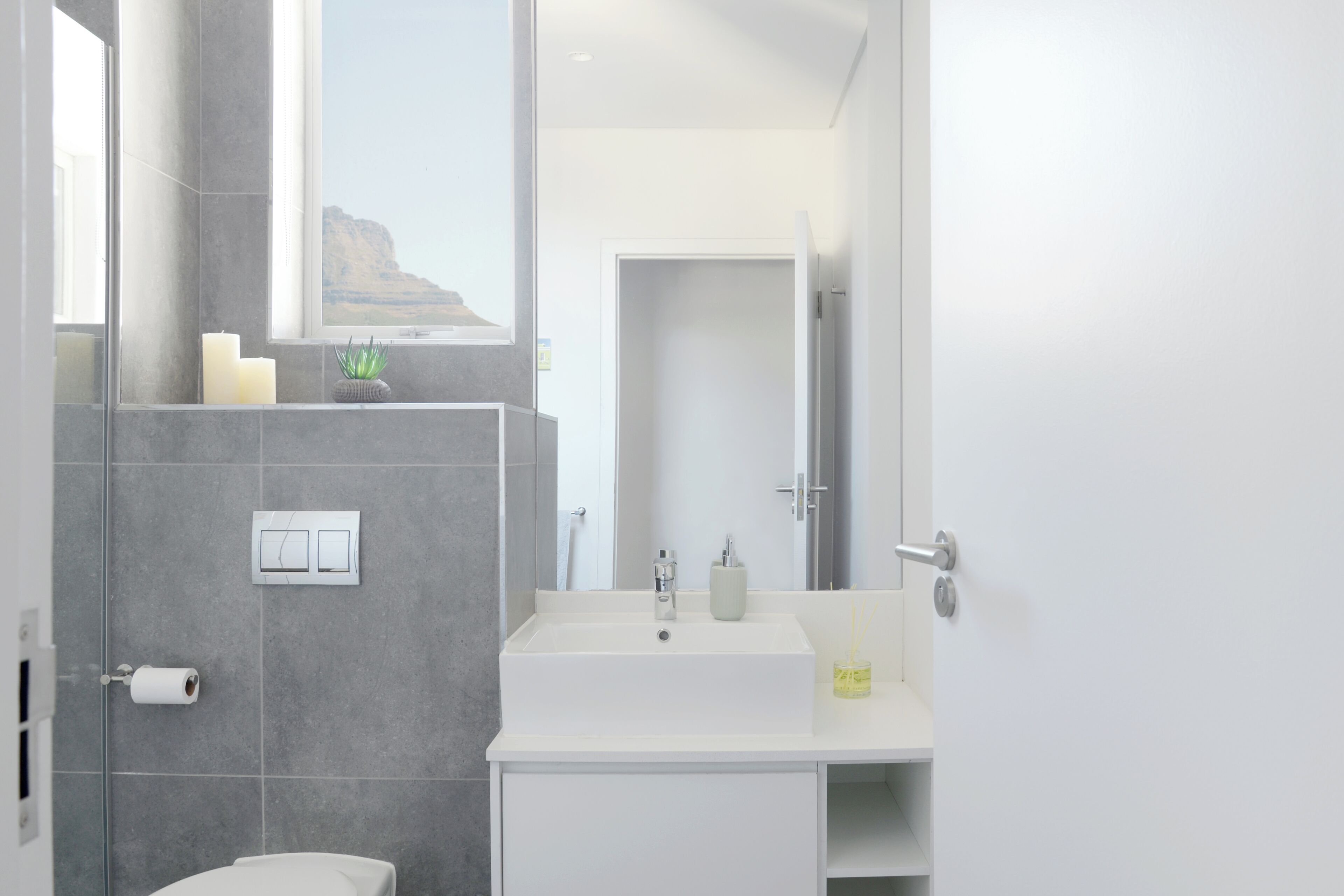 Un bagno moderno con un'ampia finestra, un lavandino bianco e un water.