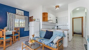 A compact living space with a sofa, dining table, and kitchen area. - Sea View Apartment Blue Pearl - Vista del Guanche (Arico)