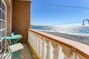 Un balcon avec vue sur la mer, une table avec des chaises et un banc.