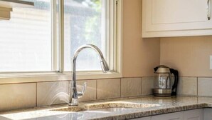 A kitchen with a stainless steel faucet, a coffee maker, and a dishwasher. - Tranquil Home in Bracewood Community of Calgary Southwest Alberta. (Calgary)
