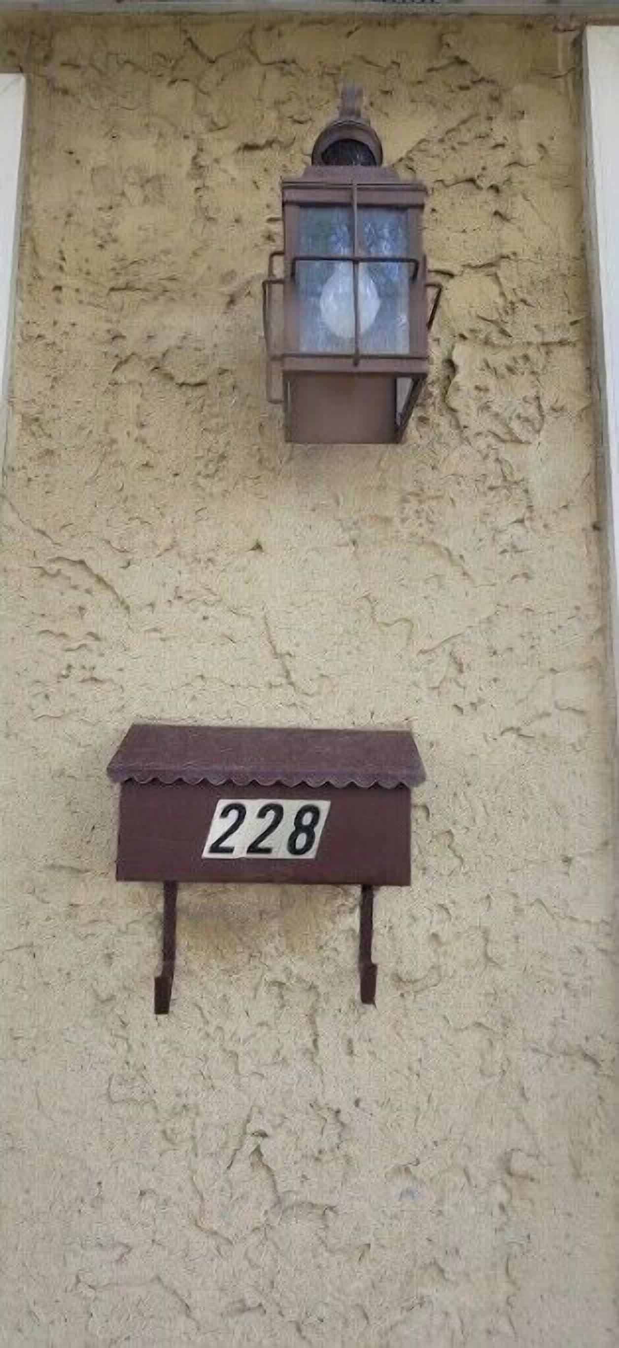 Una placa con el número '228' fijada a una pared con textura.