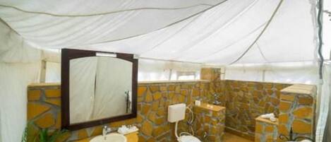 A bathroom with a stone wall, a sink, a toilet, and a mirror.