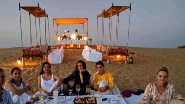A group of people dining on a beach with a tented dining area in the background. - Golden Rose Heritage Desert Safari Camp  (Jaisalmer)