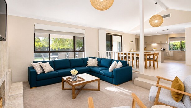 A modern living room with a sectional sofa, a coffee table, and a dining area with a table and chairs. - Gifford Getaway (Dunsborough)