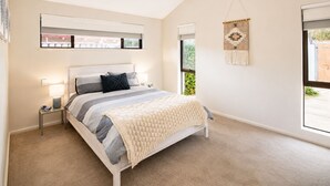 A bedroom with a bed, bedside tables, a hanging light fixture, a window, and a wall-mounted macrame piece. - Gifford Getaway (Dunsborough)