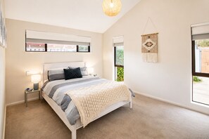 A bedroom with a bed, bedside tables, a hanging light fixture, a window, and a wall-mounted macrame piece. - Gifford Getaway (Dunsborough)