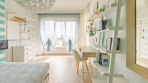 A bedroom with a bed, a desk, a chair, a wardrobe, and a bookshelf.
